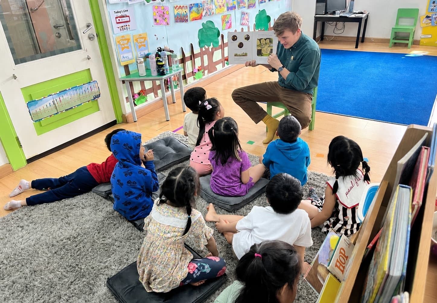 Ruaridh reading a picture book to a group of primary pupils in a classroom
